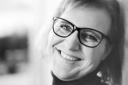 Young woman with glasses and piercing looks laughingly into the camera