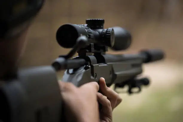 Sniper shooting rifle by looking through a scope.