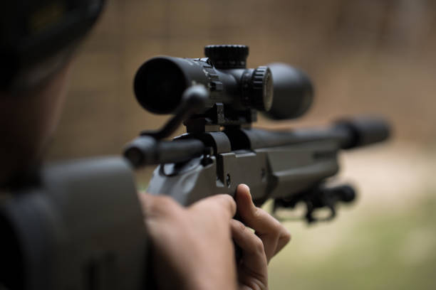 sniper shooting rifle by looking through a scope. - rifle shooting target shooting hunting imagens e fotografias de stock