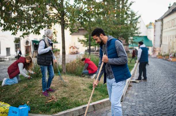 young man volunteer with team cleaning up street, community service concept - müşterek bahçe stok fotoğraflar ve resimler