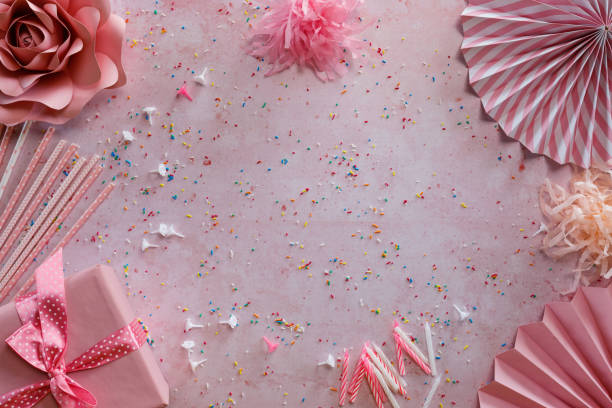 Various birthday party accessories on pink background, table top view.