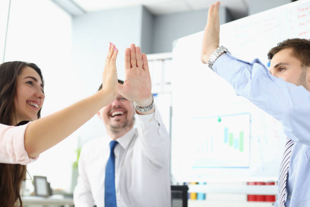 istock Team clapping hands together giving high five to celebrate finished business project 1357831768