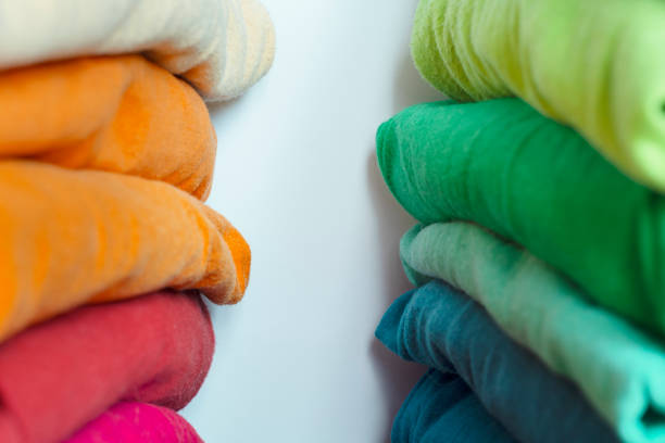 Stacks of multicolored fabrics in cool and warm colors are compared next to each other. Background with folded clothes with blank space for information. T-shirts of different colors