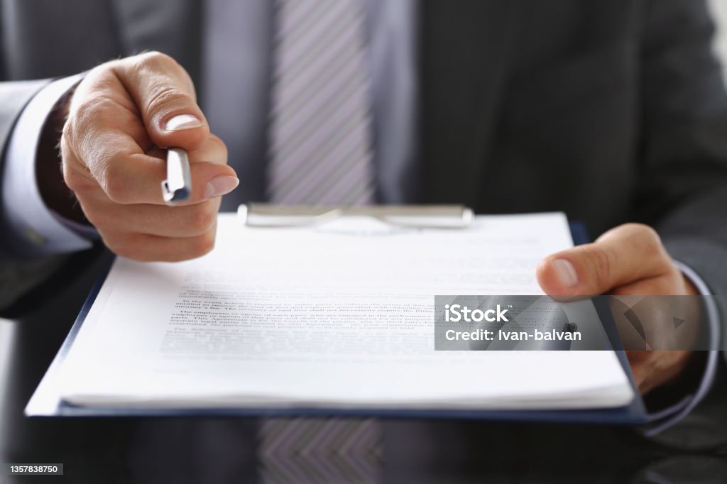 Businessman propose to sign paper, give silver pen to make deal on document Close-up of businessman propose to sign paper, give silver pen to make deal on document. Prepared business papers for client. Business, success concept Contract Stock Photo