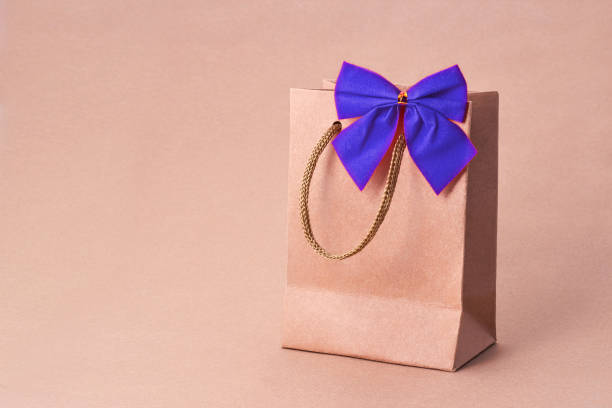 istock gift bag with a blue bow on a brown background. kraft paper. gift 1357839297