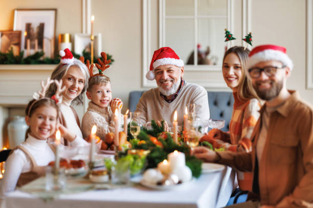 istock Happy multi generation family in Santa hats at dinner table, smiling and looking at camera 1357841604
