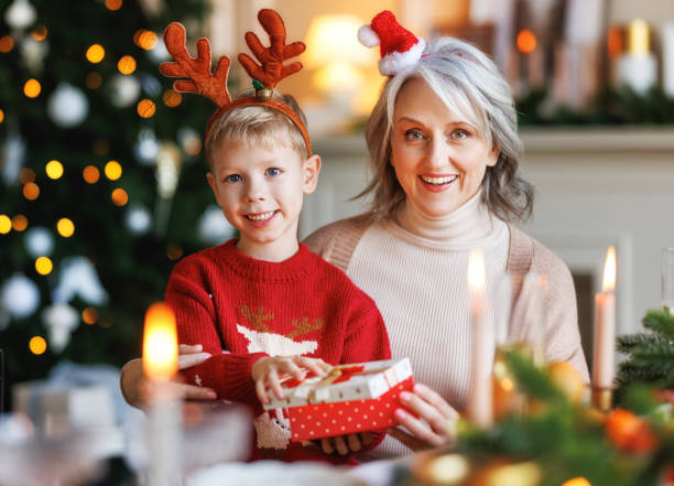 装飾されたクリスマスの木の近くにクリスマスギフトボックスを開梱興奮した女の子の孫と祖母 - 18807 ストックフォトと画像