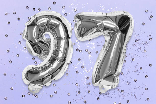 istock Silver foil balloon number, digit ninety seven on a lilac background with sequins. Birthday greeting card 1357844027