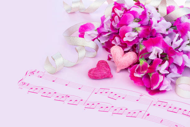 Sheet music on a white piano decorated with white flowers and candles.