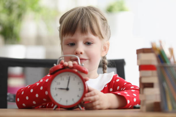 istock Cute child learn how to understand time and play with red retro clock 1357846219