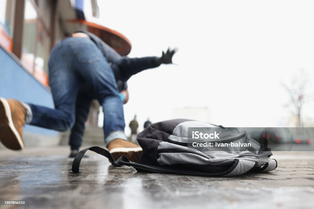 Person get injury after falling on slippery ground in winter season Close-up of person get injury after falling on slippery ground in winter season. Personal backpack lay on asphalt ice. Accident, trauma, clumsy concept Falling Stock Photo