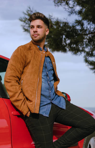istock Handsome guy leaning on a red car with his hands in the pockets 1357846281