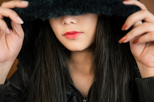 Portrait of beautiful woman in black hoodie and covering her half face