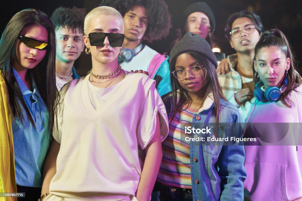 Group of cool teenager friends with funky style looking to the camera at night after music video dance performance party. Focus on African American girl Fashion Stock Photo
