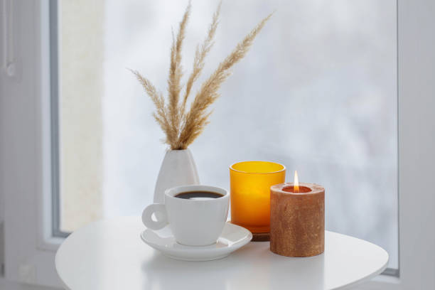 istock cup of coffee with burning candles  on white table by window on winter 1357847988