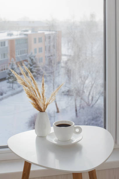 istock cup of coffee on white table by window on winter 1357847999
