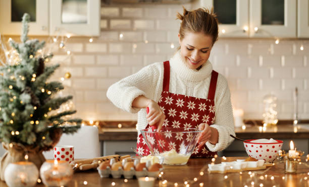 jovem sorridente mulher bonita em avental fazendo massa para biscoitos de gengibre de natal na cozinha - baking cake making women - fotografias e filmes do acervo