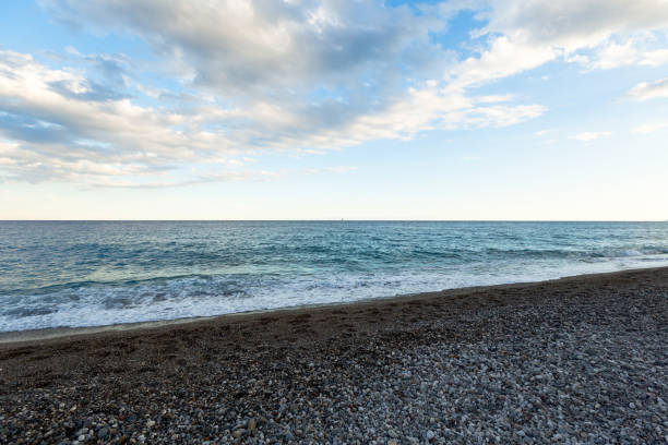 istock beautiful sea shore with blue water with pebbles 1357853450
