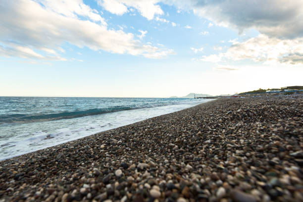 istock beautiful sea shore with blue water with pebbles 1357853528