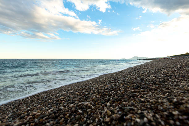 istock beautiful sea shore with blue water with pebbles 1357853531