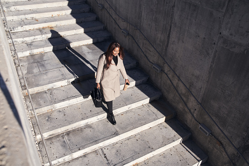 Top view of young African-American businesswoman going down the stairs