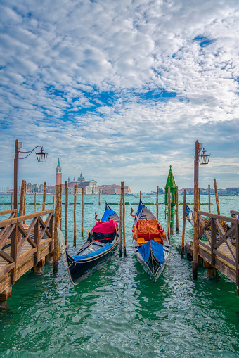 Three water taxis moored at Venice Lagoon, Venice, Italy.   Shiny and clean vessels.   Church of San Giorgio Maggiore in the background.   Blue skies with line of white clouds.   Morning with light from left side of photo. Hi by