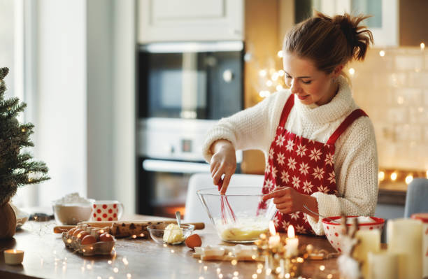 jovem sorridente mulher bonita em avental fazendo massa para biscoitos de gengibre de natal na cozinha - baking cake making women - fotografias e filmes do acervo