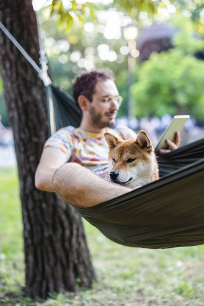 uomo che si rilassa con il suo cane nel parco e legge e-book - men reading outdoors book foto e immagini stock