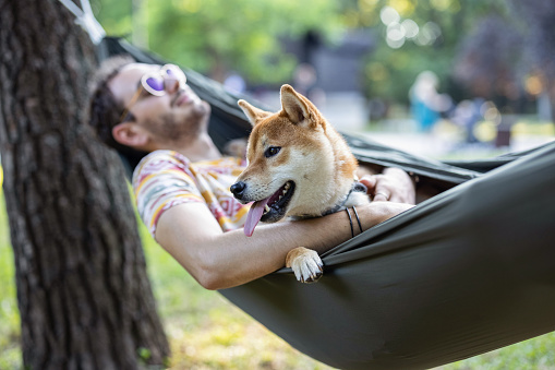 Young man and his Shiba Inu dog relaxing in the park
