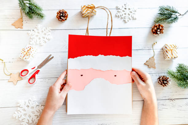 istock DIY Step-by-step guide instructions for Christmas paper bag for children. New year pack with Santa made of colored paper, glue and scissors. Fine motor skills. Winter holidays time. Handmade. Step 9 1357854756
