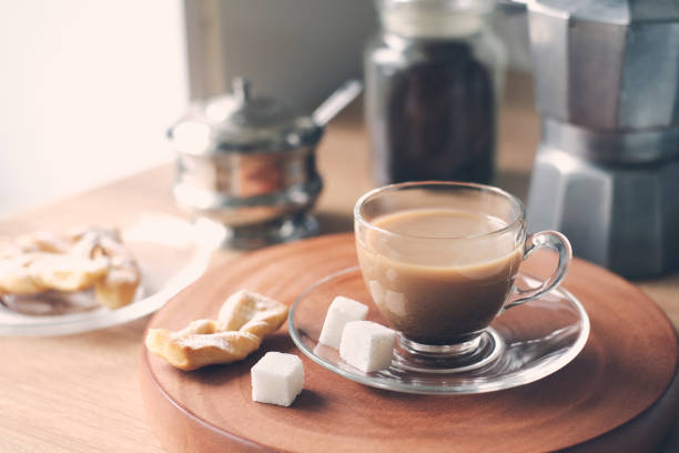 Morning still-life in the kitchen during breakfast with the jar of coffee, beans, coffee pot, sugar bowl, sugar cubes, fresh homemade cakes and cup of latte. Ideas of storage kitchen, healthy home cooking. selective Focus. light and bright mood. Good morning and Tasty Breakfast concept. Table Setting theme. High quality photo