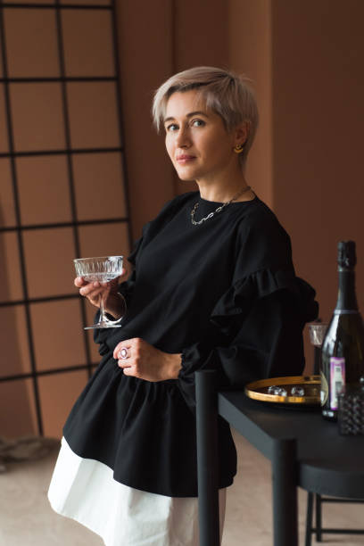 mode frau kurze blonde haare in vintage schwarz-weiß kleid mit elegantem glas für cocktail - jabot stock-fotos und bilder