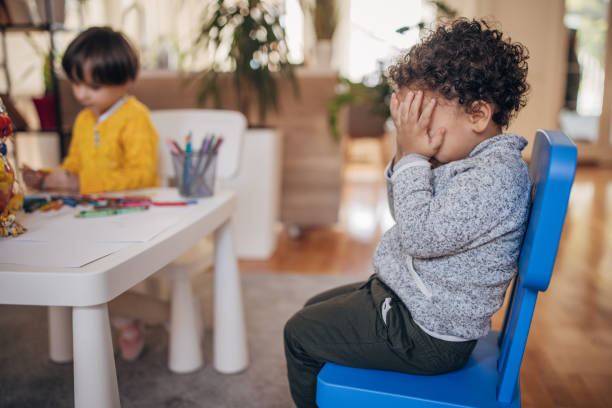 Boy crying in preschool Two people, girl playing while boy is crying in preschool classroom. preschool building photos stock pictures, royalty-free photos & images