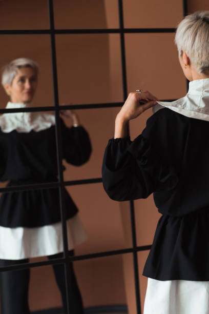 modefrau in vintage schwarz-weiß kleid stehendem braunem hintergrund blickend in die kamera - jabot stock-fotos und bilder