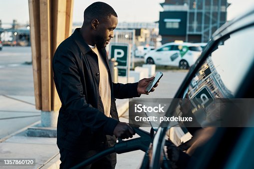 istock Cropped shot of a handsome young man recharging his electric car at a gas station 1357860120