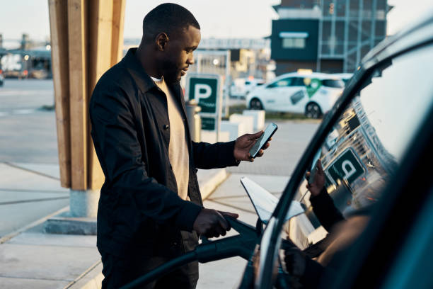 Cropped shot of a handsome young man recharging his electric car at a gas station stock photo