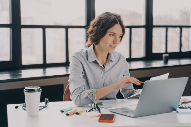 istock Young successful european businesswoman in formal wear analyzing documents at work 1357862019