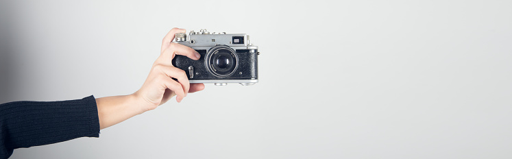 Vintage Camera in female hand on grey background