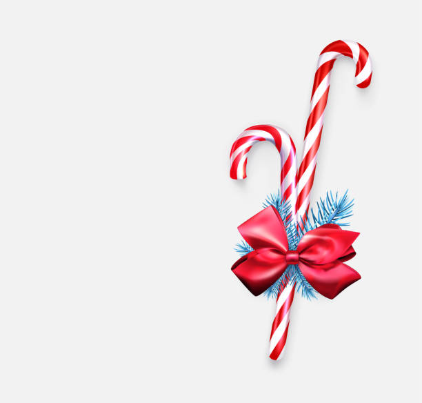 istock Two striped candy cane sticks with blue fir branch and red bow. 1357864710