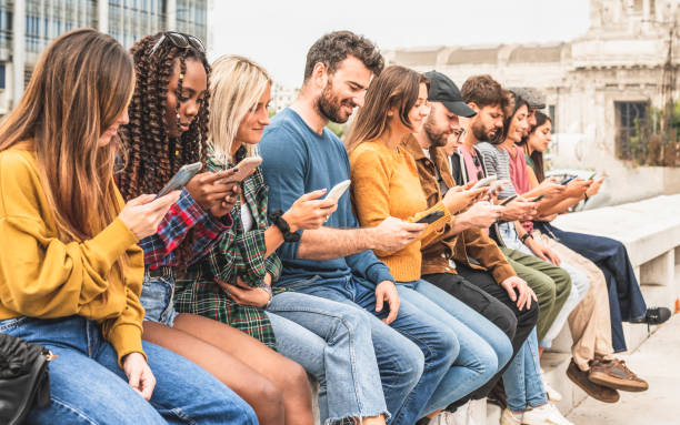 gran grupo de personas sentadas al aire libre y mirando teléfonos inteligentes, redes sociales y concepto de joven adicto a los medios - grupo grande de personas fotografías e imágenes de stock