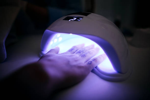 My nails are finished a little more Customer puts his hand in the dryer with a UV lamp in a beauty salon uv protection photos stock pictures, royalty-free photos & images