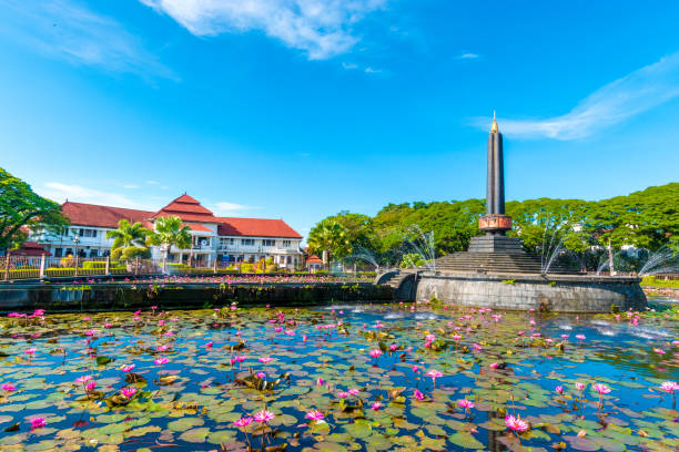 malang tugu square with blue sky and beautiful garden flower park is located in front of city hall (balai kota). it is also called as round square since due to it's round shape (alun-alun bunder) - malang stockfoto's en -beelden