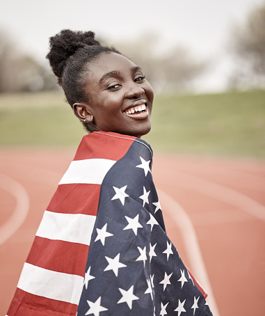 Young casual female waving a USA flag and running isolated on white background