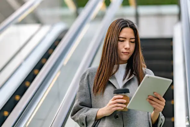 A beautiful mixed-race businesswoman is using a digital-tablet while commuting in the city.