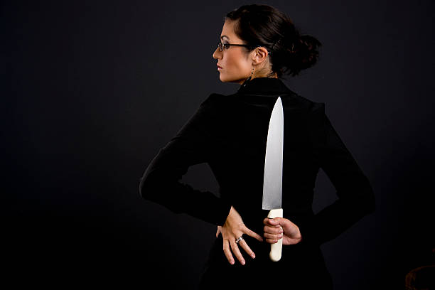 istock Knife Blade Kitchen Cutting Utensil Behind Back Woman in Black 135787476