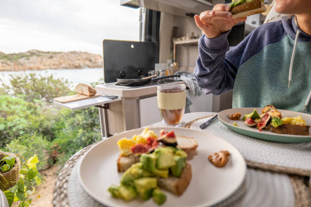 istock Low angle close up view on woman having breakfast in her camper van with a stunning beach view 1357875512