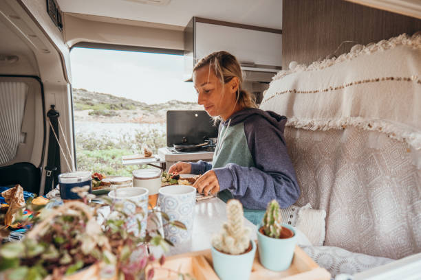 istock Woman cooking in her van, beach view 1357875603
