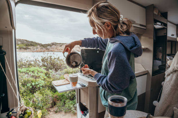 istock Woman prepares hot tea in her van, beach view 1357875763