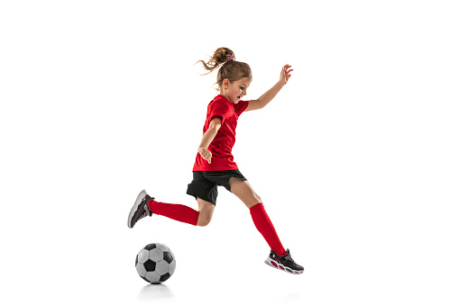 Portrait of little girl, child, training, playing football isolated over white background. Dribbling exercises. Concept of action, sportive lifestyle, team game, health, energy, vitality and ad