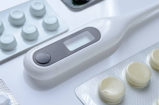 istock tablets in a package and a white electronic thermometer on a white surface close-up. 1357876013